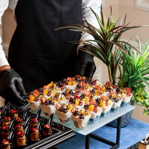 a cup of dessert with whipped cream, strawberries, cherries and orange